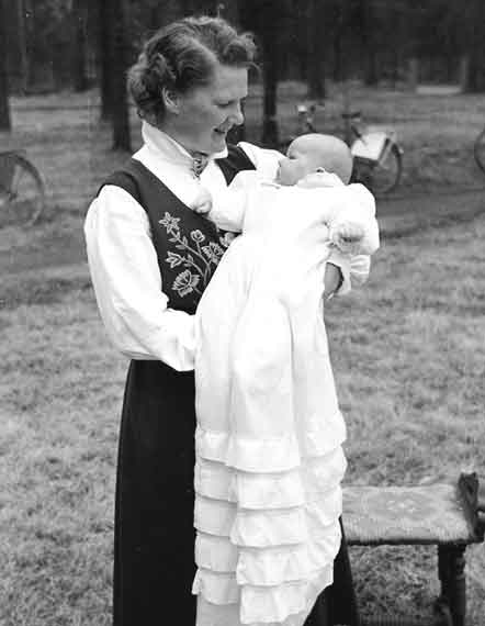 Norwegian Woman Looks Down While Holding Baby Wearing Long White Gown On Day Of Christening 1920