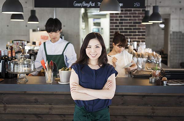 Happy Business Owner Asian Restaurant With Employees Behind Her Promotes Products Through Exciting Online Video Marketing