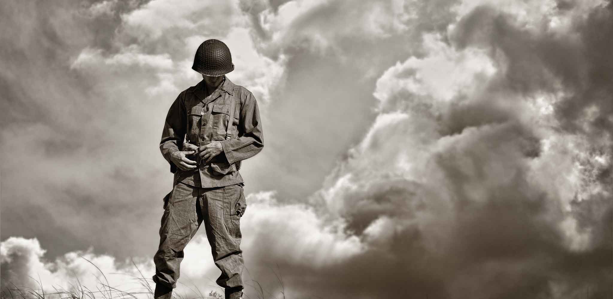 Dramtic Photograph Image WWII Soldier Standing Peacefully With Head Down Against Background Of Clouds In Sky